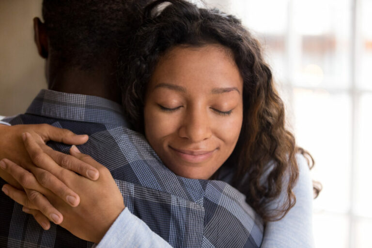 Happy african american wife hugging husband holding tight feeling grateful, smiling woman in love embracing beloved man, young black couple cuddling, support, sincere devotion and affection concept