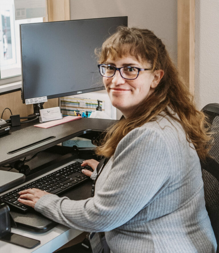 Employee sitting at their computer smiling