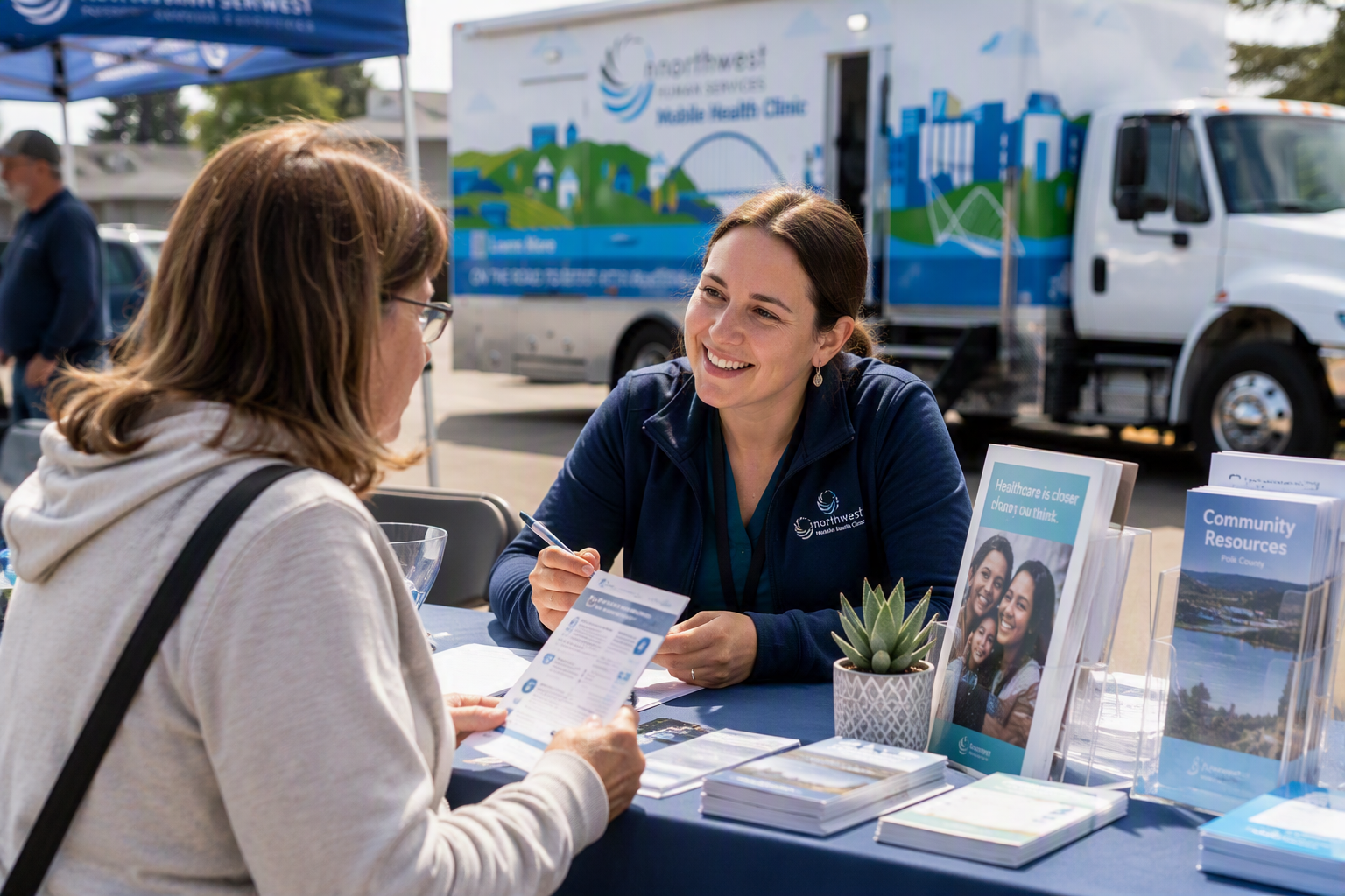 Community health navigator connecting a community member to healthcare resources at a mobile health clinic event.